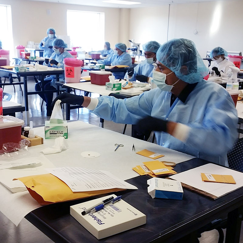 a classroom of DNA analysts practice in protective clothing