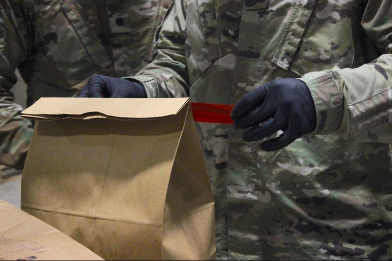 A trainee packages evidence on a scene using paper bags and security tape.