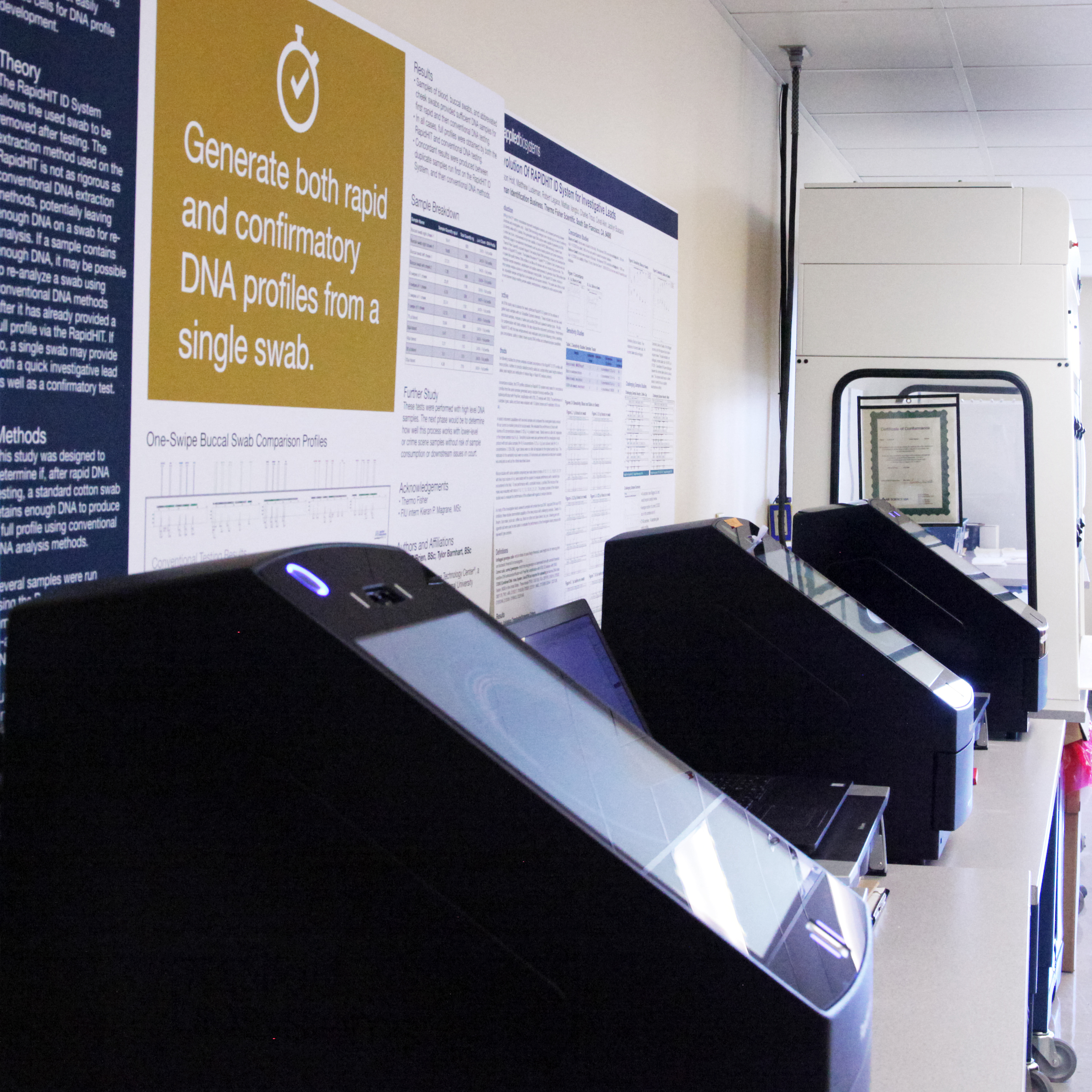 A row of rapid DNA machines sit on a laboratory table.