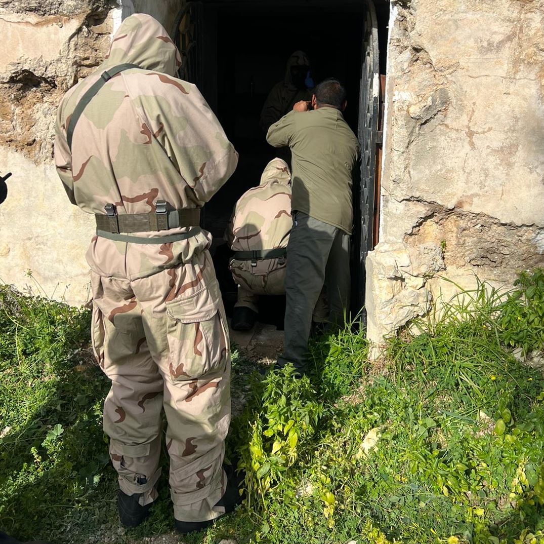 investigators in protective clothing enter an enclosed space with an instructor